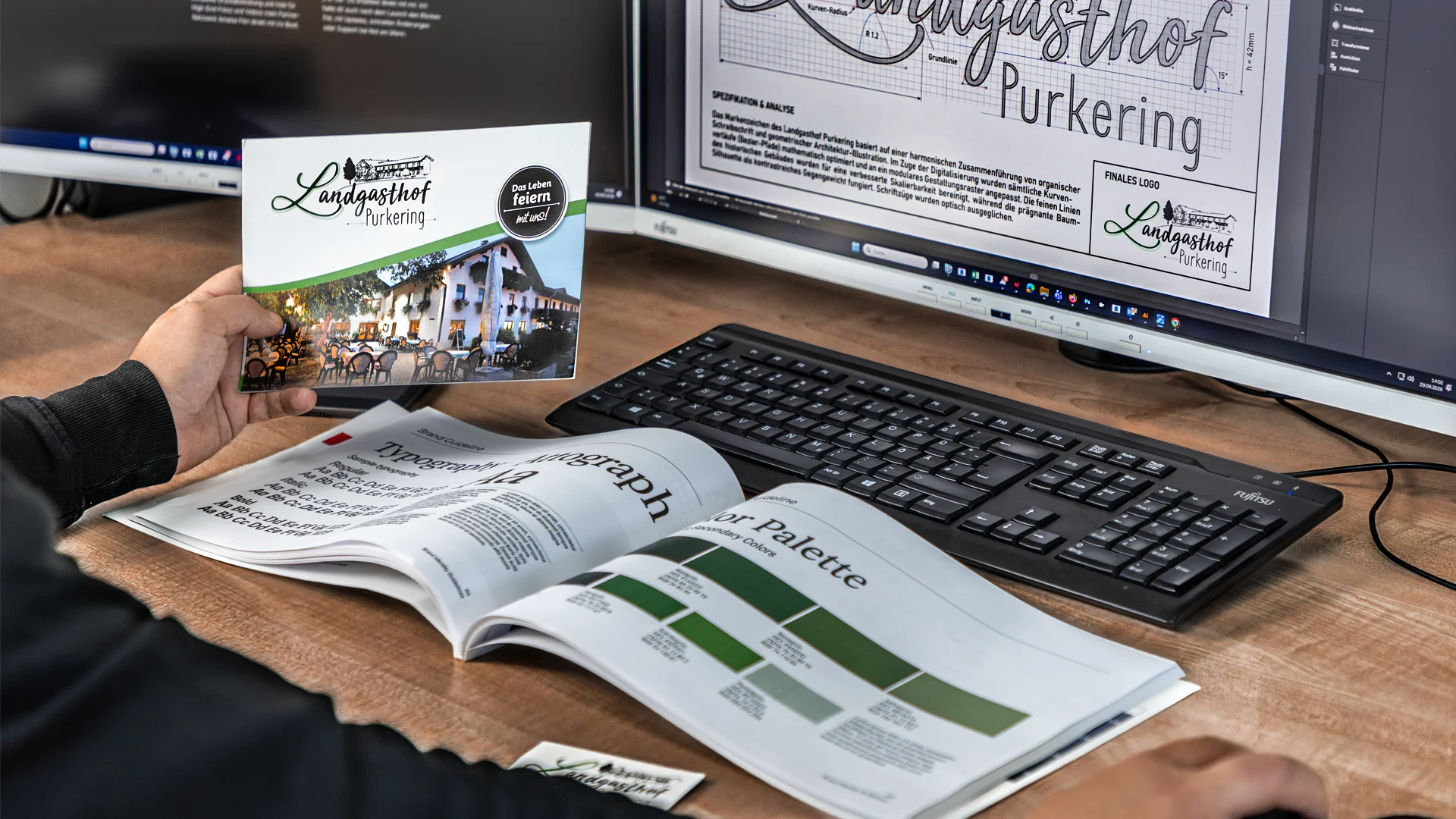 Grafikdesign-Arbeitsplatz mit gedrucktem Flyer, Brand-Handbuch und Logo-Entwurf für den Landgasthof Purkering