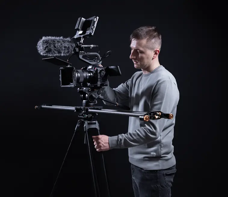 Videograf mit Kamera-Rig und Stativ im Studio